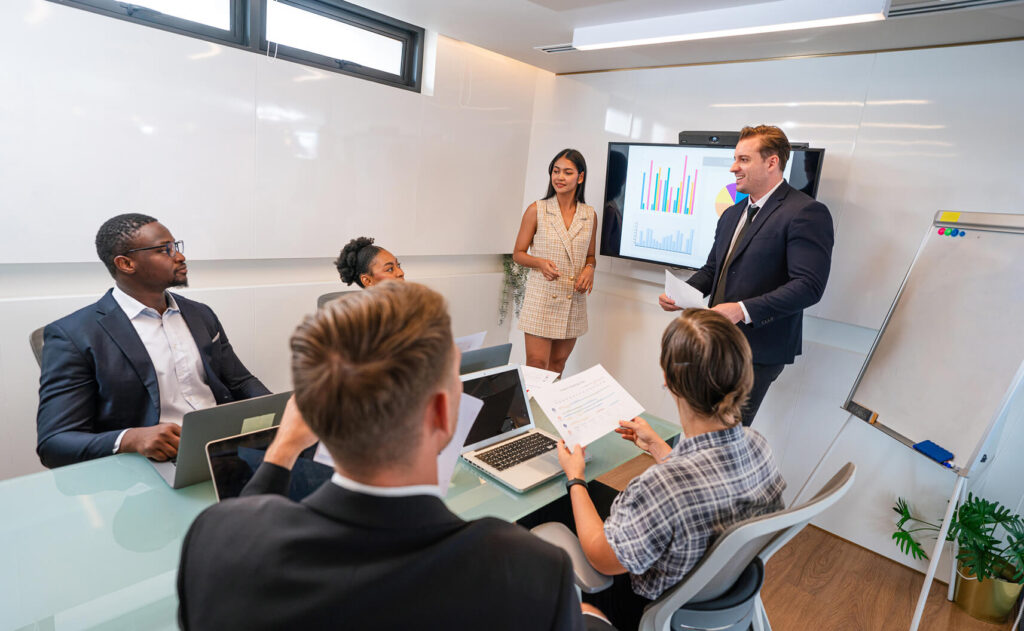 Team of professionals in a conference room participating in Spotfire training, with a business presenter leading data visualization training on an interactive dashboard, showcasing collaborative learning as part of a hands-on Spotfire course and Spotfire bootcamp.